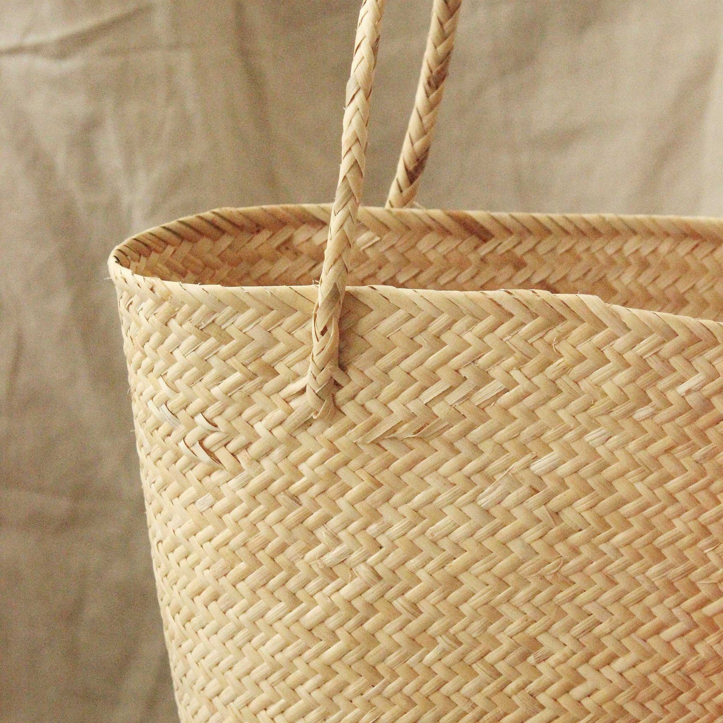 Handwoven straw beach bag made from natural rattan, featuring pom-poms and tassels.
