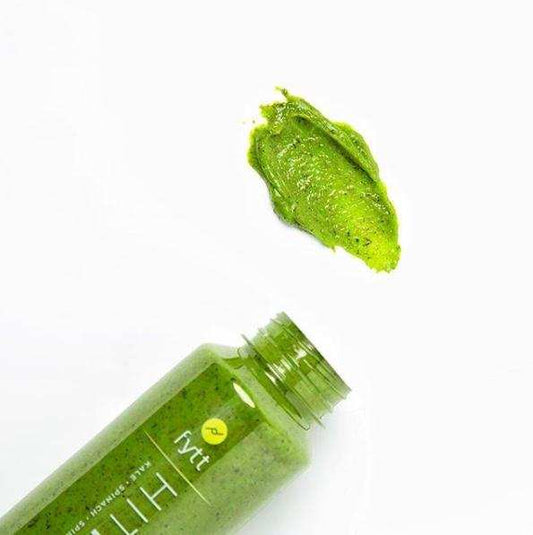 Green detoxifying exfoliating face and body mask with natural plant-based ingredients and creamy texture spilled from bottle